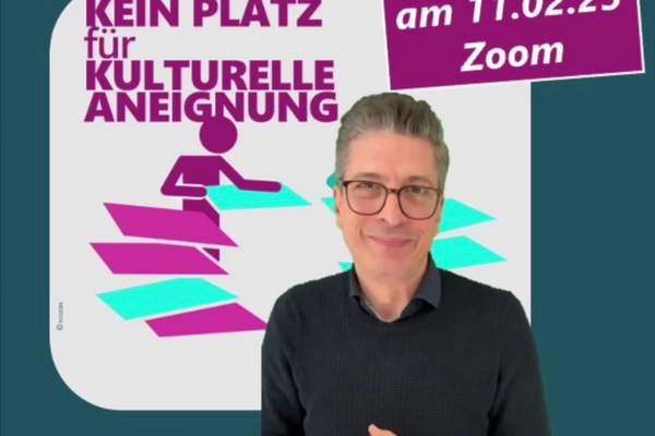 Ein Mann mit kurzen schwarzen Haaren mit Brille und dunklem Pullover steht vor einem dunklen petrolfarbenen Hintergrund